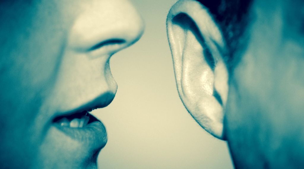 Woman whispering in man's ear, close-up (B&W)